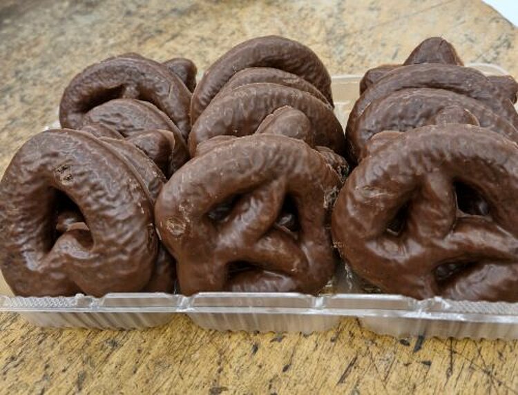 Schoko-Lebkuchenherzen und Brezeln in einer Verpackung stehen auf einem Holztisch.